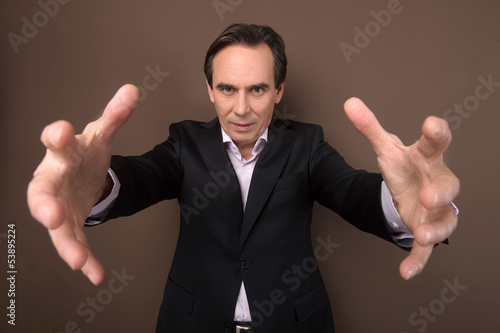 Give it all to me! Confident mature businessman trying to grab s photo