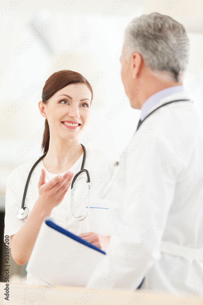 Consulting with a colleague. Young female doctor standing in fro