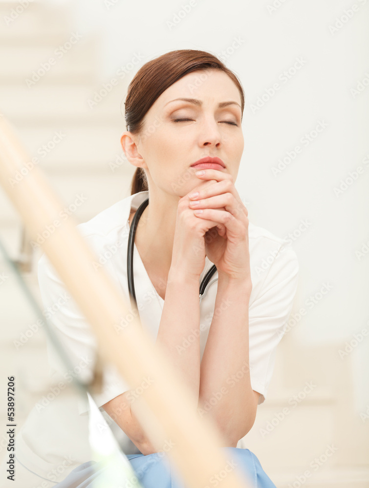 Tired and depressed. Beautiful young female doctor sitting at th