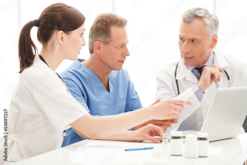 Medical doctors team using computer. Medical doctors team going Medical doctors team using computer. Medical doctors team going