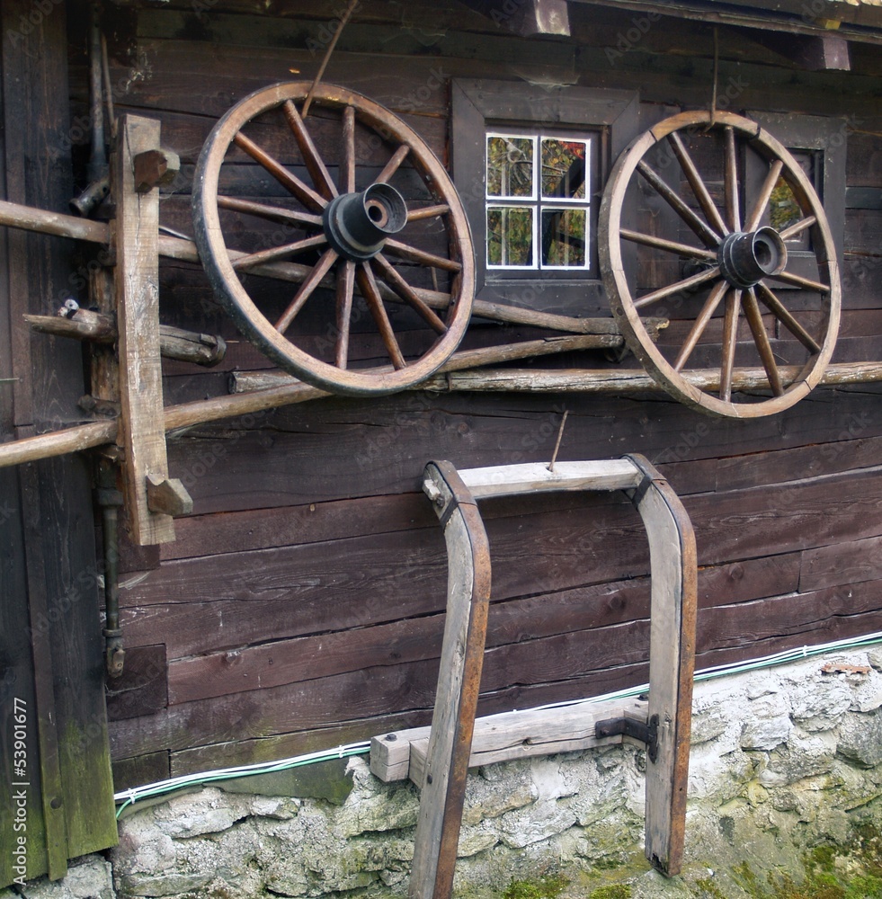 Obraz premium Wagon wheel on old log house