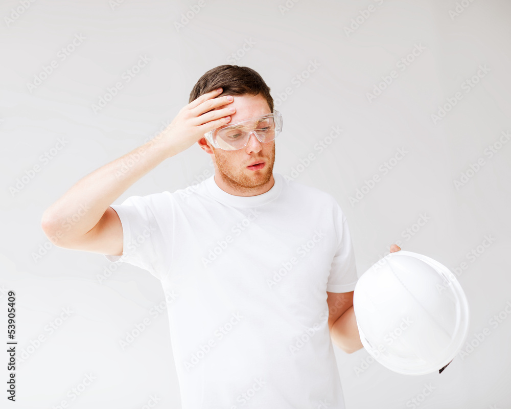 male architect in safety glasses taking off helmet male architect in safety glasses taking off helmet
