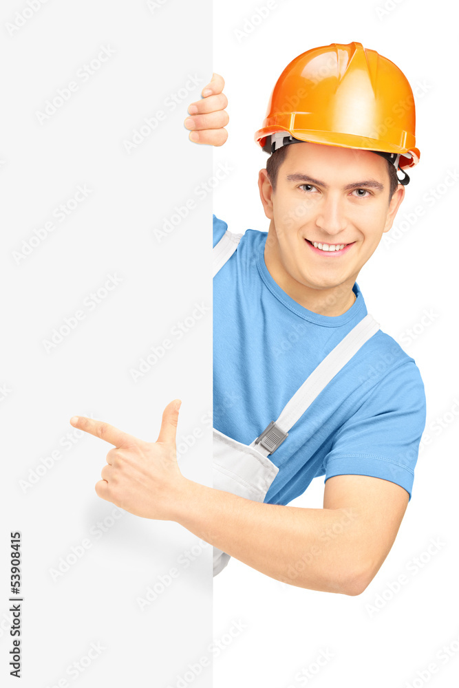 Young smiling construction worker with helmet pointing on a pane Young smiling construction worker with helmet pointing on a pane
