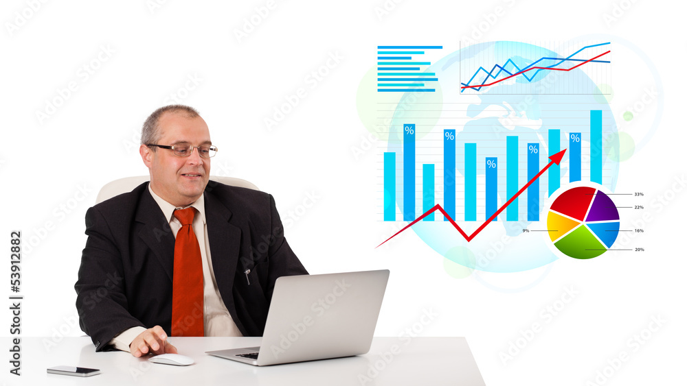 Businessman sitting at desk with laptop and statistics Businessman sitting at desk with laptop and statistics