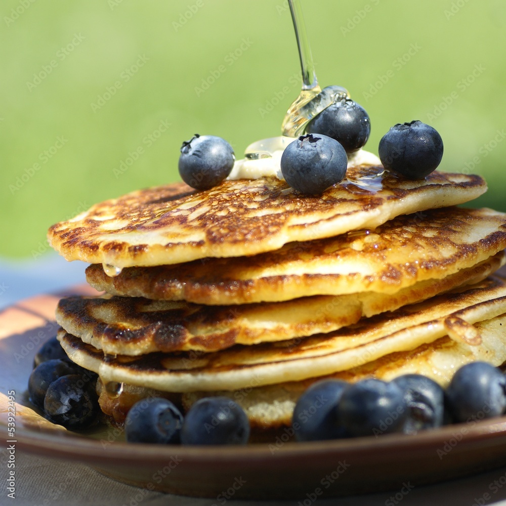 Pouring syrup on pancakes with blueberries. Pouring syrup on pancakes with blueberries.