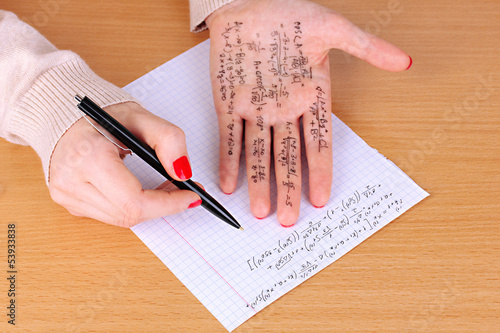 Write cheat sheet on hand on wooden table close-up photo