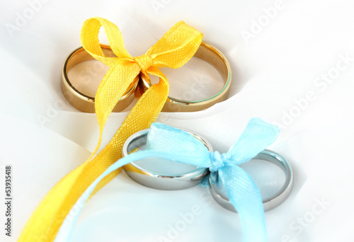 Wedding rings tied with ribbon on cloth background