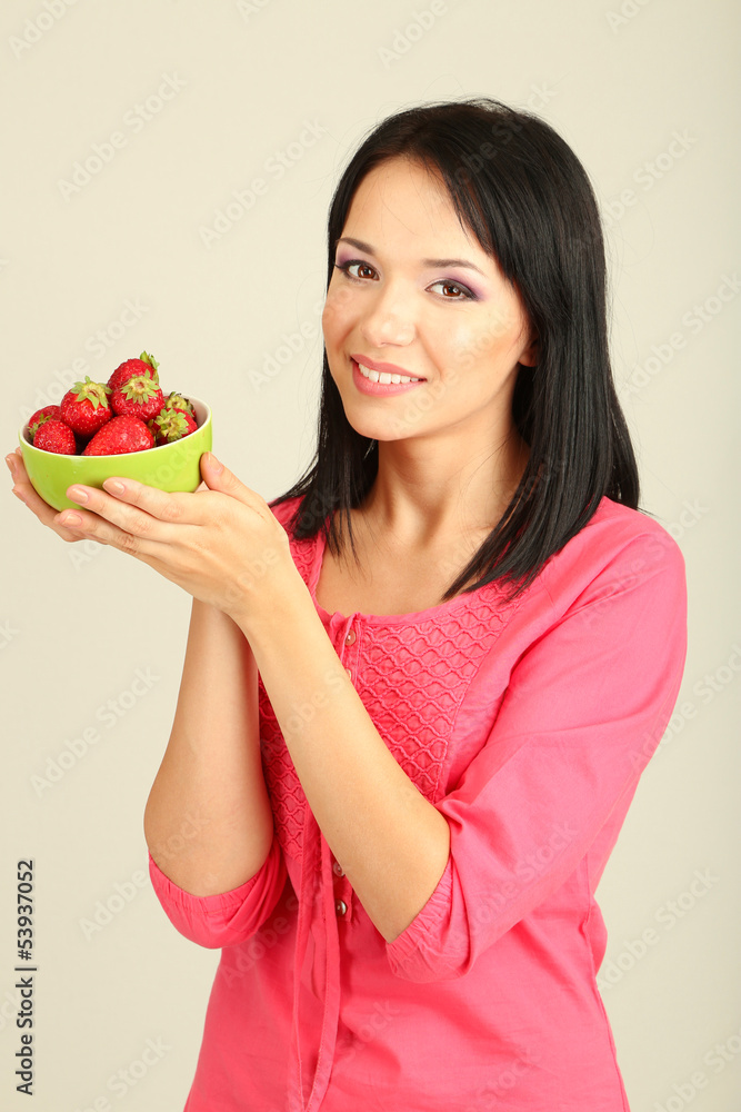 Beautiful young woman with strawberries on grey background Beautiful young woman with strawberries on grey background