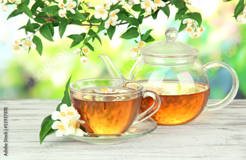 Cup of tea with jasmine, on wooden table, on bright background