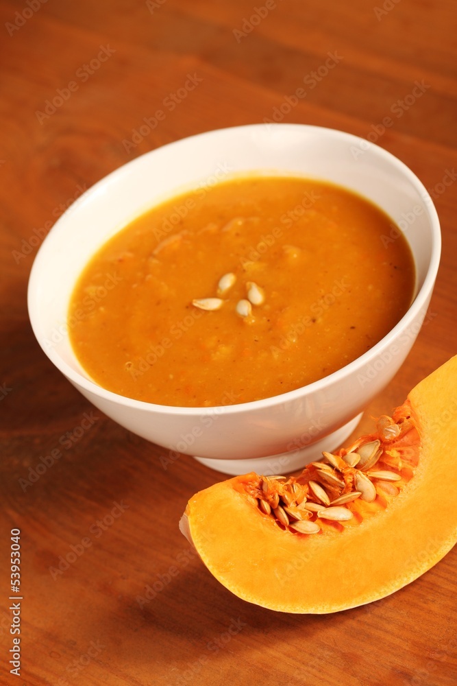 Bowl with pumpkin soup and slice of fresh pumpkin Bowl with pumpkin soup and slice of fresh pumpkin