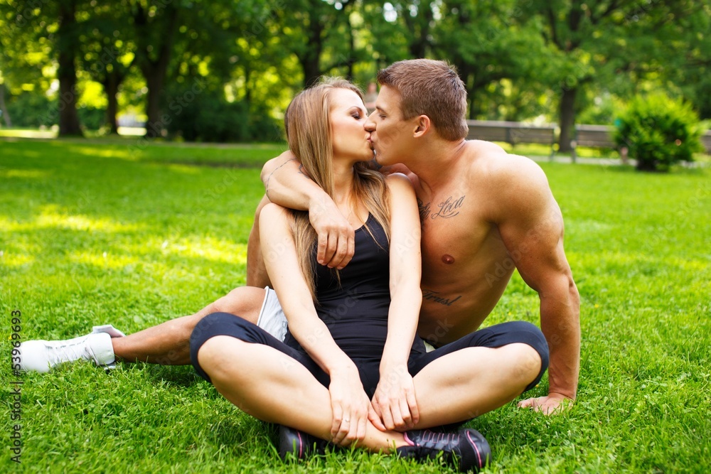 Fototapeta premium Young happy smiling sporty couple sitting on a meadow