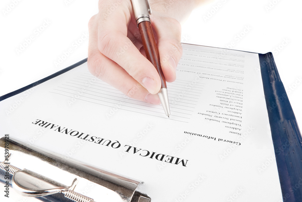 Hand filling in medical questionnaire form in a clipboard Hand filling in medical questionnaire form in a clipboard