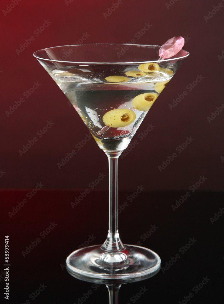 Martini glass with olives on dark red background