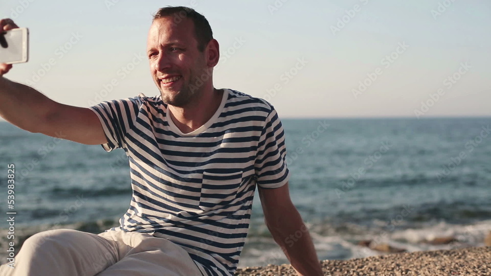 Man taking photo of himself with smartphone by the sea Man taking photo of himself with smartphone by the sea