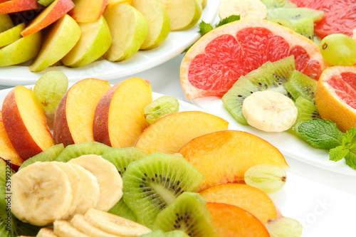 Assortment of sliced fruits on plates, close up
