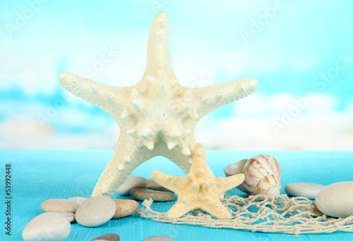 White starfishes on blue wooden table on sea background