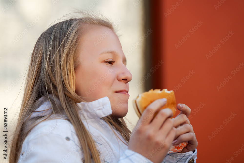 Teenage girl eating a burger