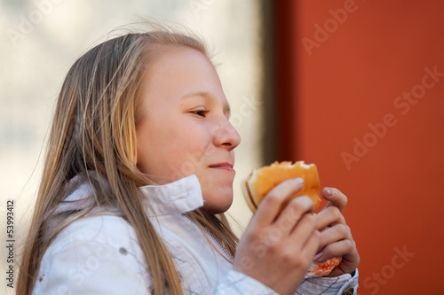 Teenage girl eating a burger