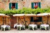 Cafe tables and chairs outside a stone building in Tuscany