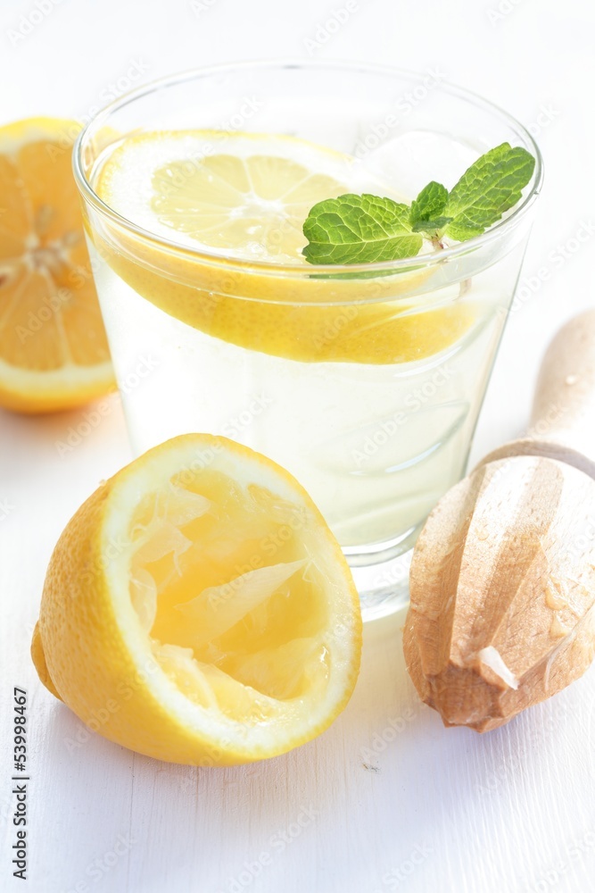 Glass of fresh lemonade with lemon and mint and wooden squeezer. Glass of fresh lemonade with lemon and mint and wooden squeezer.