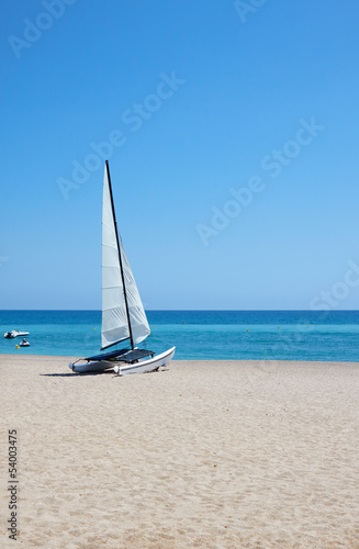 White sailboat on perfect tropical white sand beach © ZoomTeam