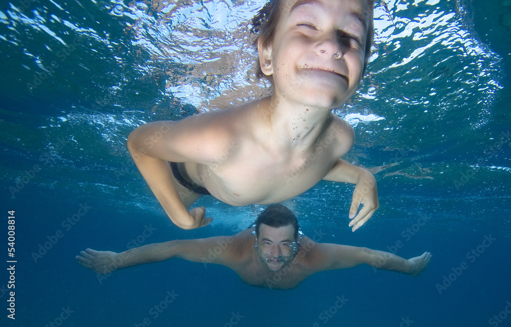 Happy boy swimming with his father  in a sea