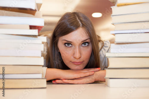 Frau legt Kopf zwischen zwei Bücherstapel photo