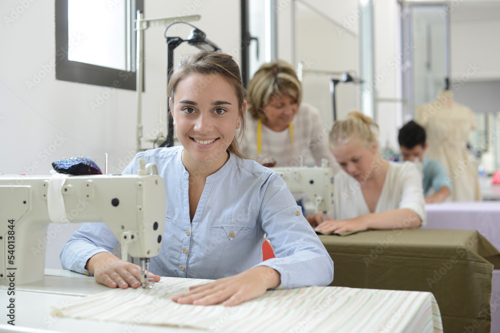 Obraz premium Student girl in training class working on sewing machine