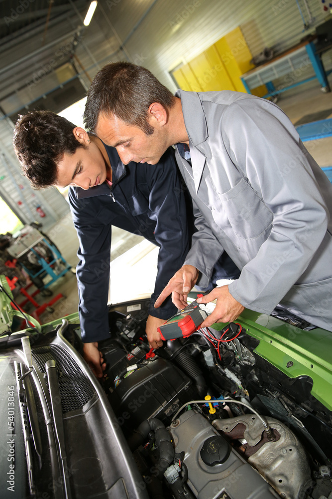 Trainer with student in repairshop checking on battery Trainer with student in repairshop checking on battery
