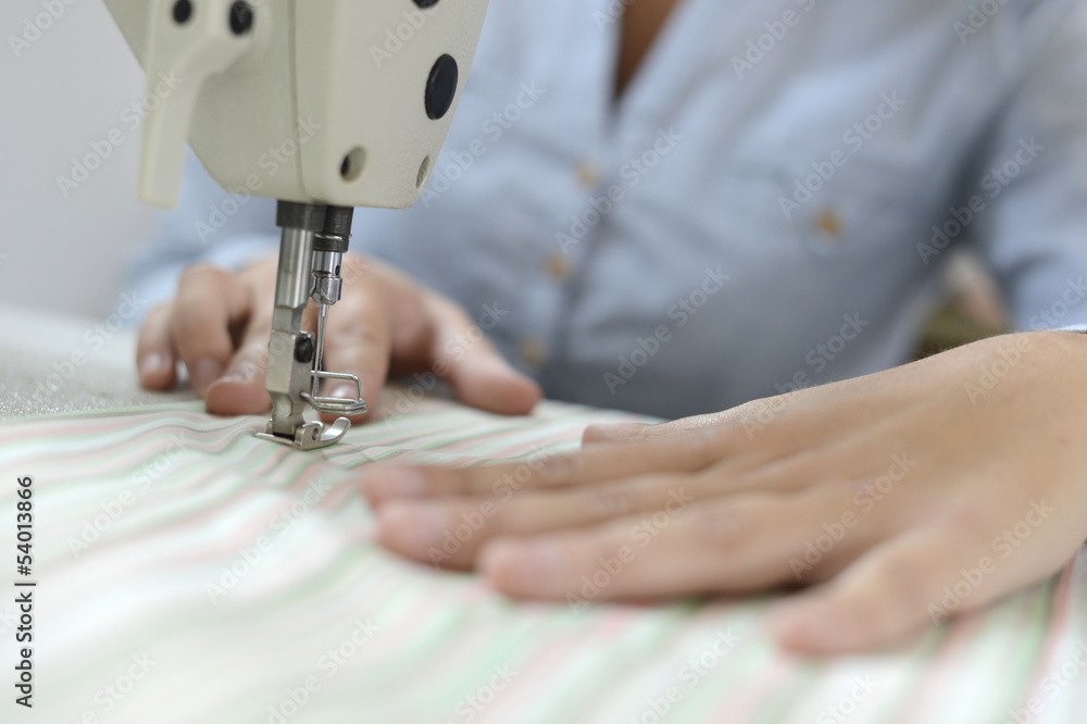 Closeup on dressmaker hand using sewing machine