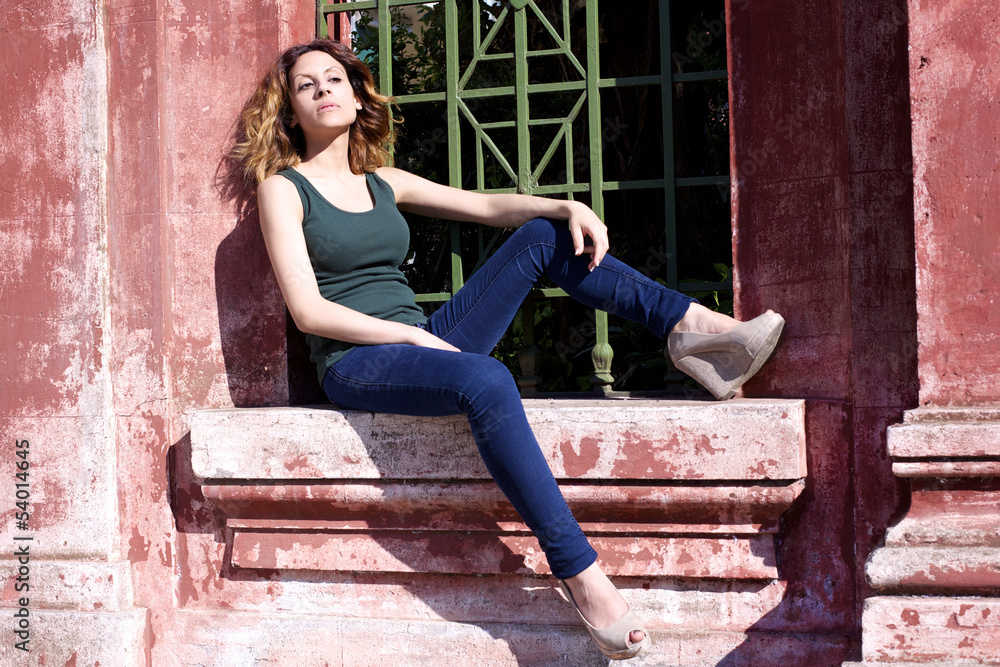 Woman posing sitting in front of red wall Woman posing sitting in front of red wall