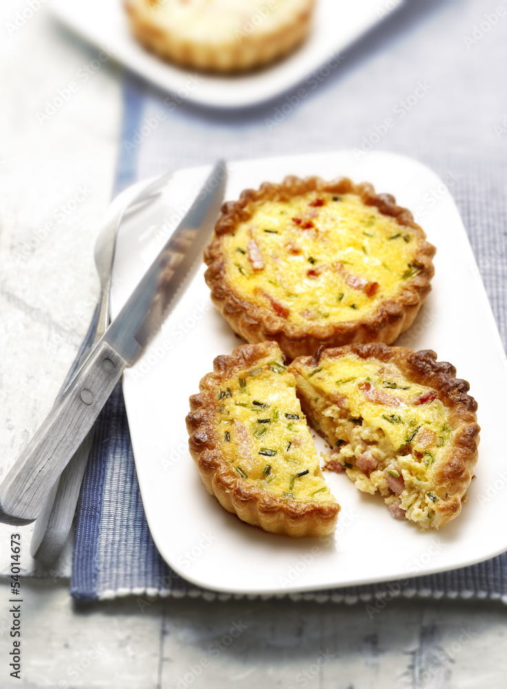 two quiches with bacon on a plate one cut in half