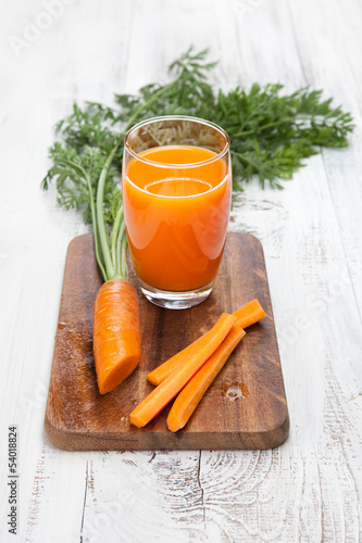Carrot juice with fresh carrots on white table