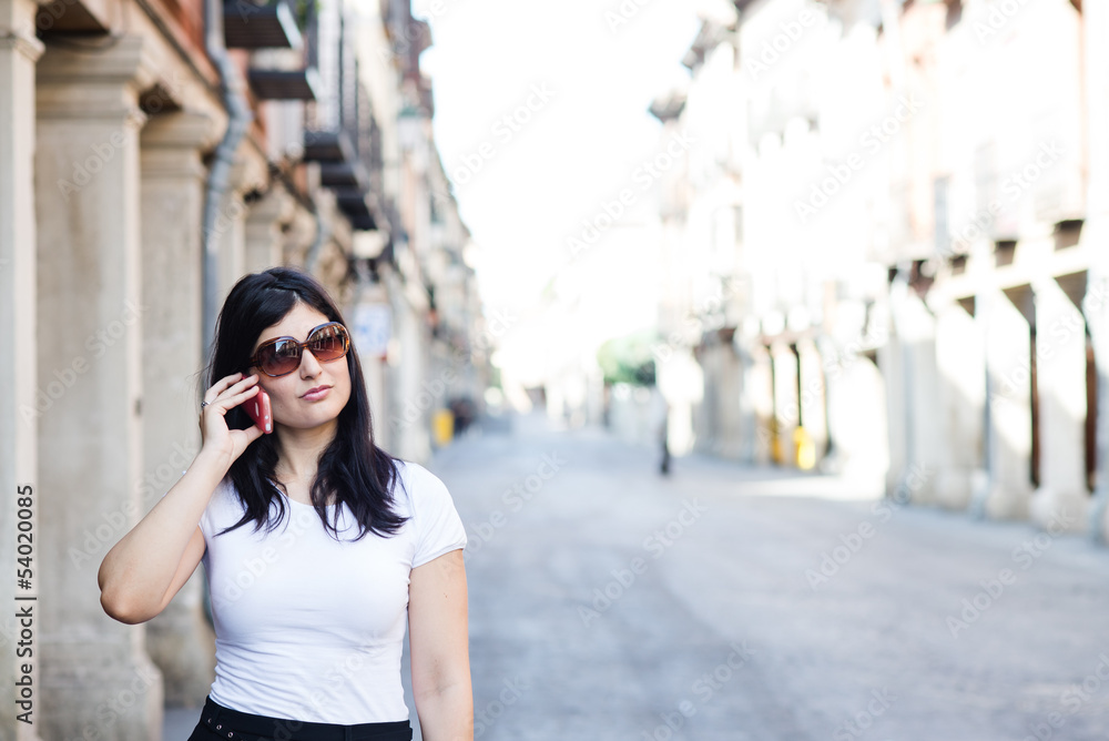 Fototapeta premium Girl with sunglasses waiting and talking to her smartphone
