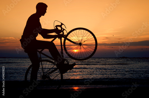 Riding a bicycle at the sunrise on the beach