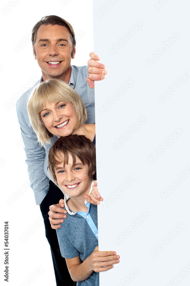 Family of three behind blank whiteboard Family of three behind blank whiteboard