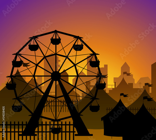 Ferris wheel and circus silhouette in front of a city