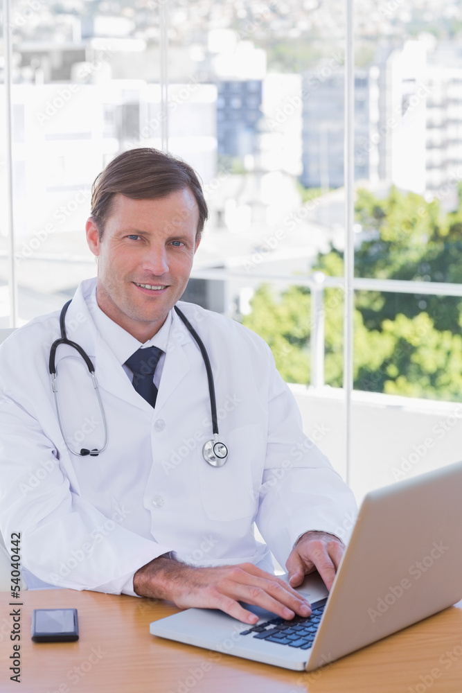 Smiling doctor working on his laptop Smiling doctor working on his laptop