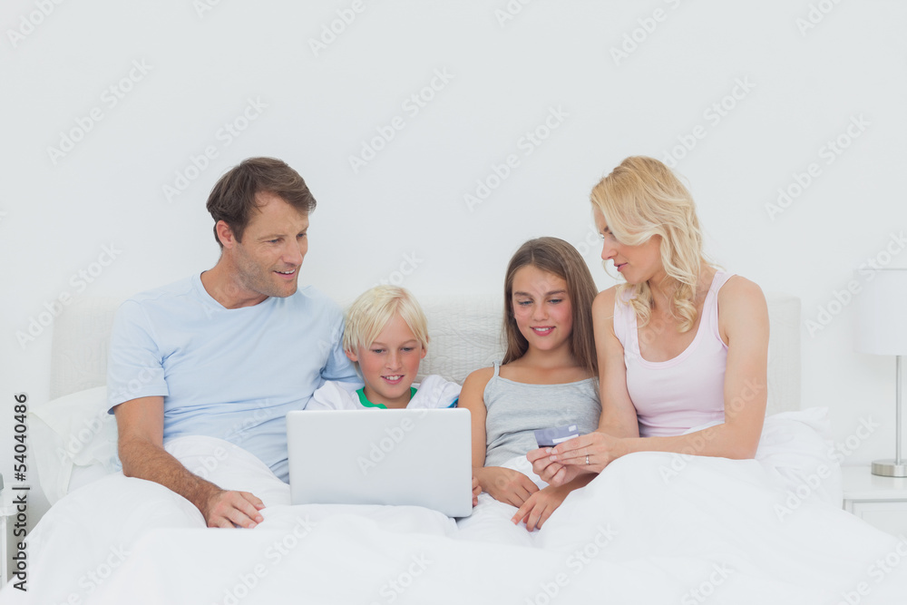 Family sitting in bed and using a laptop Family sitting in bed and using a laptop