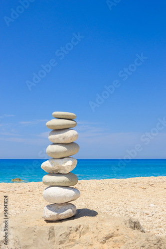 Pebbles stack balance over blue ionian sea in Greece