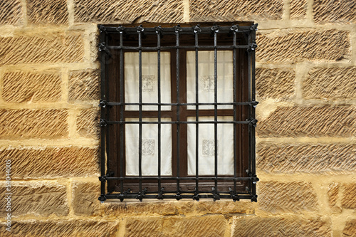 Ventana con reja en muro de piedra photo