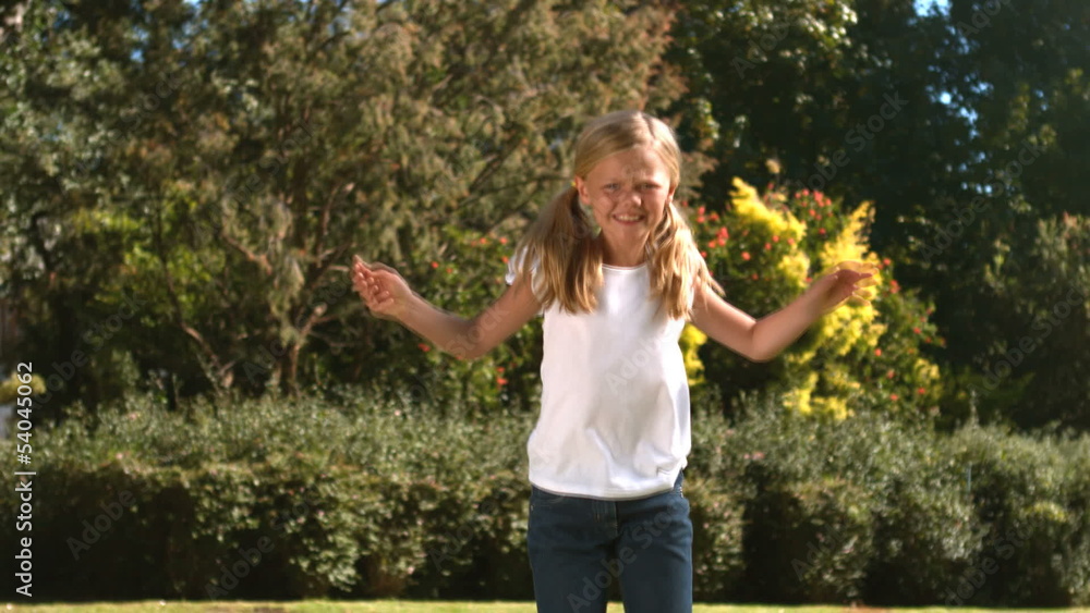 Cheerful little girl jumping in her garden in slow motion Cheerful little girl jumping in her garden in slow motion