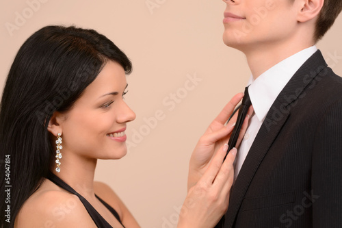 Tying his tie. Beautiful young woman tying his boyfriends tie