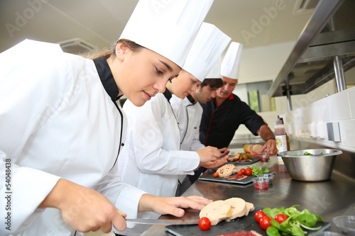 Fototapeta Team of young chefs preparing delicatessen dishes