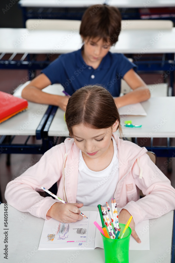Schoolgirl Drawing At Desk In Classroom Schoolgirl Drawing At Desk In Classroom