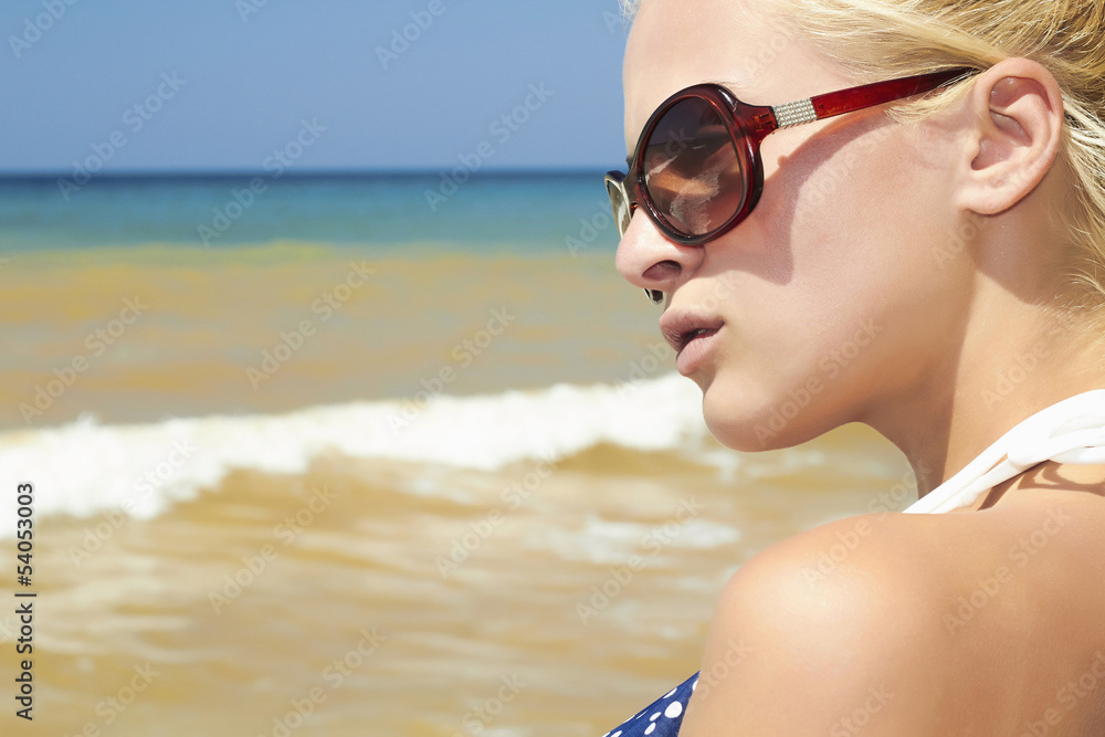 Beautiful blond woman on the beach in sunglasses
