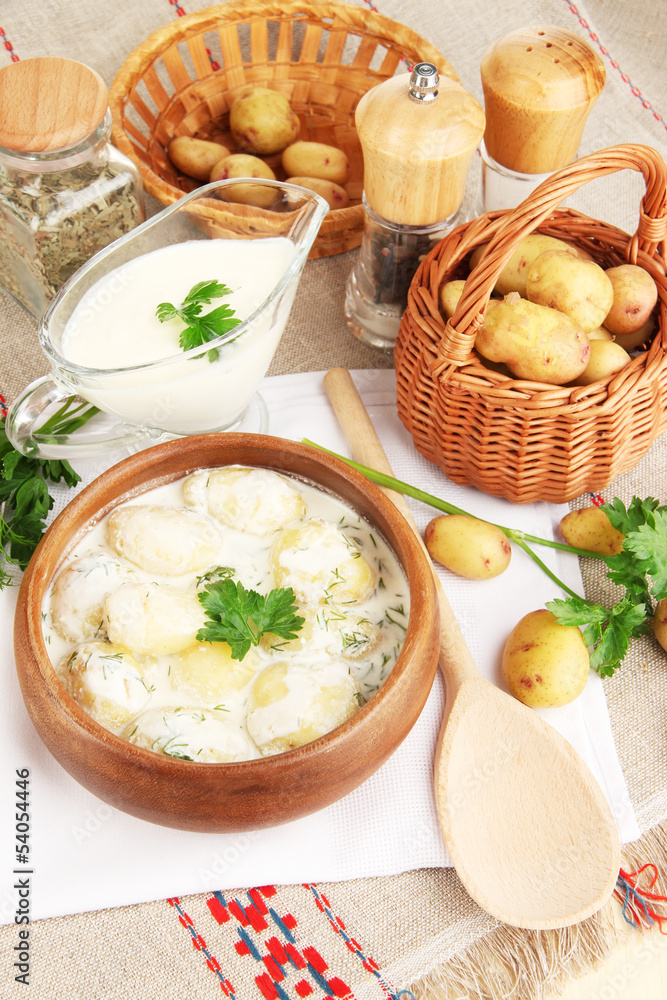 Tender young potatoes with sour cream and herbs in wooden bowl Tender young potatoes with sour cream and herbs in wooden bowl