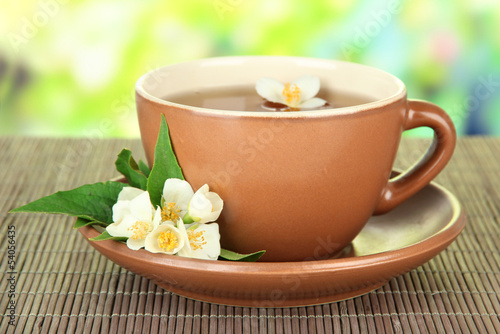 Cup of tea with jasmine, on bamboo mat, on bright background