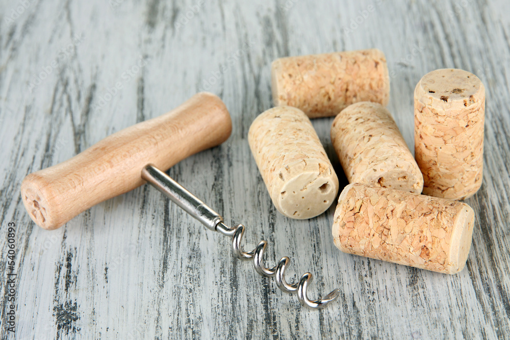 Corkscrew with wine corks on wooden table close-up
