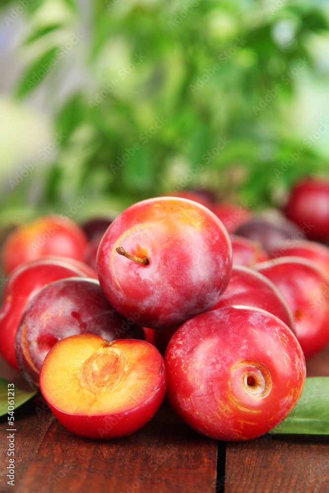 Ripe plums on wooden table on natural background